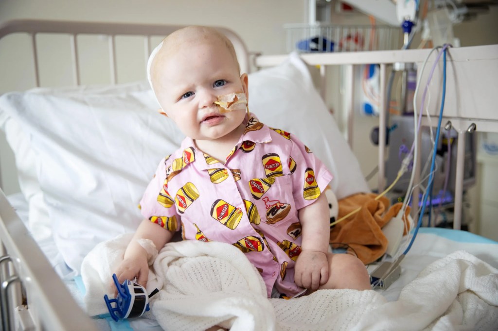 Tiny Marilou sitting on a hospital bed looking adorable in her pink Vegemite Pj's